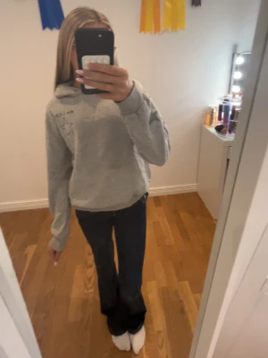 Grå hoodie med stjärnor och text - Grå hoodie med huva och tryckta gråa stjärnor längs ärmarna. På bröstet finns texten 'MA CHÉRIE' och en liten stjärna. Tyvärr har den en liten rosa och en liten orange fläck men dom stans inte så mycket. Sen har den heller inga snören