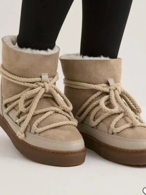 Beige moon boots med snörning - Säljer ett par beige inuikki med grov snörning och högt skaft. Skorna har en mjuk, fluffig insida och ovandel i mocka. Yttersulan är i gummi och designen är chunky och trendig. Perfekta för kalla dagar och ger en cool vinterlook.