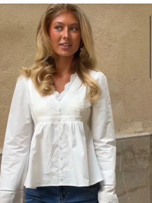 Vit blus ifrån Meet Me There - Säljer en helt ny blus med prislapp på.  Super fin blus, aldrig använd då den är förliten. Köpte en större storlek men kan ej lämna tillbaka denna. 565kr-500kr.Beskrivning från hemsidan: Din nya vita besatthet 🤍 Den här vita blusen har en romantisk känsla och är perfekt för sommaren. Knapparna framtill och V-ringningen ger en elegant look. Spetsdetaljerna och de utsvängda ärmarna gör den extra rolig att bära. Blusen kan du ändlöst kombinera med din favoritkjol eller shorts för en tjejig outfit. 