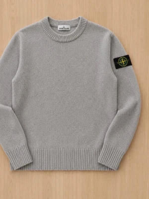 Grå stickad tröja Stone Island - Snygg grå stickad tröja från Stone Island med rund halsringning och ribbade muddar. Klassisk patch med logga på vänster ärm. Perfekt för dig som gillar stilrena plagg med en sportig touch.