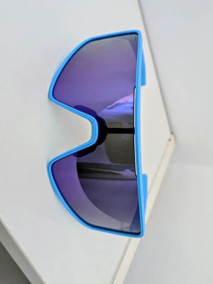 Blå sportiga solglasögon från Bliz - Säljer ett par riktigt snygga solglasögon från Bliz med sportig vibe. De har en blå ram och stora, spegelblå linser i en futuristisk, kantig form. Perfekta för dig som vill sticka ut och skydda ögonen mot solen under sommaren.