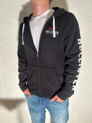 Hollister zip hoodie~vintage - Svart hoodie från hollister i storlek M. Modell är 185cm. Priset går att diskuteras vid snabbaffär. Skriv vid minsta fundering.