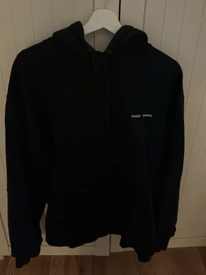 Marinblå hoodie från Samsøe Samsøe - Marinblå hoodie från Samsøe Samsøe med liten vit logga på bröstet. Klassisk modell med huva och dragsko. Perfekt för en chill och avslappnad stil. Passar till det mesta och är enkel att matcha.