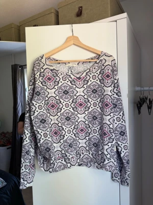 Mönstrad långärmad tröja - Säljer en långärmad tröja med vitt, svart och lila orientaliskt mönster. Tröjan har rund halsringning och avslappnad passform. Perfekt för dig som gillar unika prints och vill sticka ut lite extra. Från märket Odd Molly i storlek 3 som enligt deras storlekguide motsvarar en storlek L. Mycket fint skick, jag hittar inga synliga anmärkningar eller defekter. 