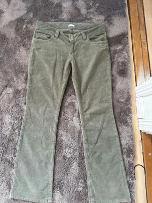 Olivgröna bootcut manchesterbyxor - Säljer ett par helt nya olivgröna manchesterbyxor med bootcut-modell från Nelly. Nypris är 699 kr. Byxorna har dubbla knappar i midjan och snygga sömdetaljer på bakfickorna. Perfekta för dig som gillar retrostil och mjukt material.
