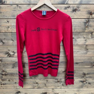 Röd långärmad topp Jean Paul Gaultier (XS-S) - Snygg röd långärmad topp från Jean Paul Gaultier med svarta ränder nedtill och på ärmarna. XS-S. Mycket gott begagnat skick.   1051