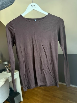 Brun långärmad topp - En enkel och stilren brun långärmad topp med rund halsringning. Tillverkad i mjukt bomullsmaterial som känns skönt mot huden. Perfekt att matcha med jeans eller kjol för en clean look. Färgen är orättvis på bild, första bilden är mest lik ton men mörkare. Jättefin brun färg