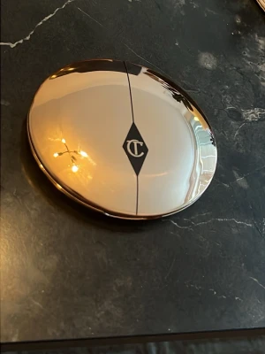 Charlotte Tilbury Setting powder medium - Säljer en Setting powder från Charlotte Tilbury i en elegant, rund guldskimrande dosa med spegel. Färgen är ljusbeige och formulan är kompakt, perfekt för en naturlig finish. Dosan har märkets logga på locket och känns lyxig att ha i väskan.