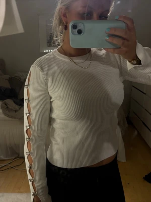 Unik tröja från Zara  -  vit ribbad tröja med långa ärmar och coola öppna detaljer längs hela ärmen, fästa med silvriga knappar. Passar bra till finare tillfällen! Andvänd en gång!