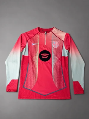 Barcelona långärmad träningströja - Säljer en långärmad träningströja från Nike för FC Barcelona. Tröjan är rosa med ljusblå ärmar och har gradient-effekt. På bröstet finns Nike-logga, Spotify-logga och Barcelona-emblem. Materialet är tekniskt och andas, perfekt för träning.