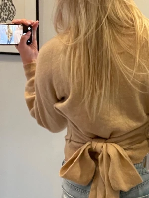 Beige stickad tröja med rosett - Stickad beige tröja i mohair/alpacka från other stories. Tröjan här även en rosett man knyter för bak. Skicka gärna prisförslag🩷