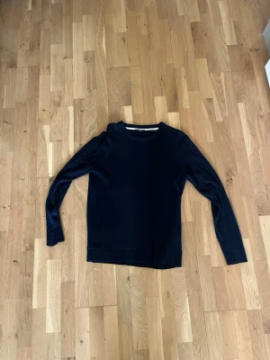 Mörkblå stickad tröja Jack & Jones - Snygg mörkblå stickad tröja från Jack & Jones med diskret kabelstickat mönster. Tröjan har rund halsringning och långa ärmar. Perfekt för dig som gillar klassisk och enkel stil.