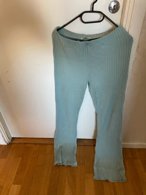Ljusblå ribbade leggings - Säljer ett par ljusblå leggings med ribbad struktur och utsvängda ben. De har elastisk midja och vågig kant längst ner vid bensluten. Perfekta för en chill och avslappnad stil.
