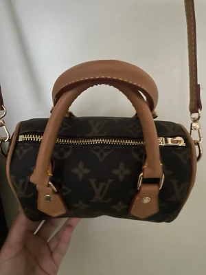 Zara väska - Snygg handväska från Zara i klassiskt brunt monogrammönster med ljusbruna läderdetaljer. Väskan har både handtag och en avtagbar axelrem i läder samt guldfärgade metalldetaljer. Perfekt storlek för det viktigaste och en ikonisk accessoar.