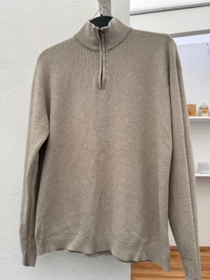 Beige stickad tröja med halv dragkedja - Snygg beige stickad tröja från Lindex med halv dragkedja och hög krage. Tröjan har lång ärm och är tillverkad i mjukt material, perfekt för en avslappnad och stilren look.