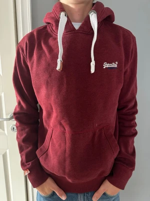 Röd Superdry Hoodie Vintage - Tja den är i storlek XL från Superdry. Modellen är 180cm så den är för stor på han. Den har inga defekter, fråga om mått eller annat.