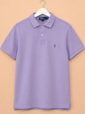 Lila pikétröja Polo Ralph Lauren - Snygg lila pikétröja från Polo Ralph Lauren med klassisk krage och två knappar framtill. Tröjan har korta ärmar och den ikoniska gröna loggan broderad på bröstet. Tillverkad i 100% merceriserad bomull. Använt skick men hel, fin och fläckfri.