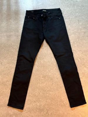Jack & Jones Glenn Slim Fit Jeans W30/L32 Svarta Fint Skick - Snygga svarta Jack & Jones Glenn Slim Fit jeans i storlek W30/L32.  Mycket fint skick och sparsamt använda. Inga hål eller fläckar. Bekväm passform med stretch och passar både vardag och mer uppklädda outfits.  Storlek: W30/L32 Modell: Glenn Slim Fit Färg: Svart  Nypris cirka 900 kr.