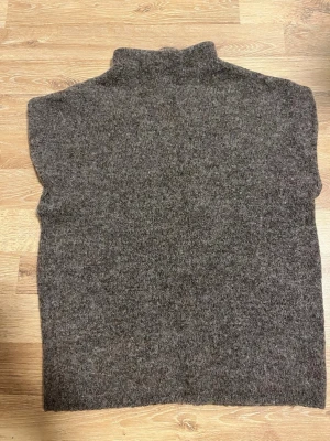 Mörkbrun stickad tröja med polokrage - Super snygg Stickad tröja i mörkbrun färg med hög polokrage och ärmlös design. 