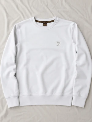 Louis Vuitton Vit - Snygg vit sweatshirt från Louis Vuitton med broderad LV-logga på bröstet. Tröjan har rund halsringning och ribbade muddar vid ärmslut och nederkant. Perfekt för dig som gillar stilrena och exklusiva plagg.