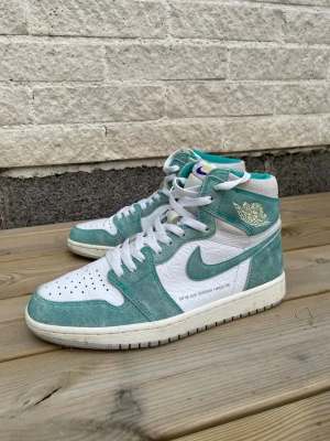 Nike Air Jordan 1 High OG Turbo Green strl 42 - Nike Air Jordan 1 Retro High OG “Turbo Green”.  Använda bara ett par gånger och fortfarande i mycket bra skick. Mocka och läder i turkos/vitt med originaldetaljer.  Storlek: 42.5 Säljes eftersom de inte används längre. Nypris runt 6000 kr.
