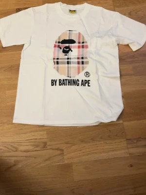 BAPE T-Shirt #1 - Vit/Burberry/Beige BAPE Tröja. Storlek: S. Aldrig använt förut och den är helt ny. Startpriset är 300kr, DM vid intresse da