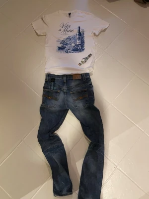 Vita di Mare t-shirt med tryck - Snygg t-shirt från Vita di Mare med stort blått vintagemotiv och text framtill. Finns i både vit och marinblå färg. Klassisk passform och rund hals. Perfekt för dig som gillar stilrena och coola prints. KOLLA PROFIL FÖR MER KLÄDER SKOR! Hör av er vid frågor!