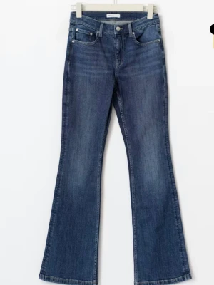 Blå bootcut jeans low waisted  - Säljer ett par blå bootcut jeans med låg midja och fem fickor. Jeansen har en klassisk tvätt och raka ben som går ut lite nedtill. Perfekta till sneakers eller boots och ger en avslappnad men snygg look.