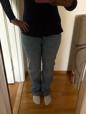 Ljusblå raka jeans - Säljer ett par ljusblå jeans med rak passform och klassisk femficksdesign. Jeansen har normal midja och stängs med dragkedja och knapp. Perfekta för en avslappnad och stilren look.