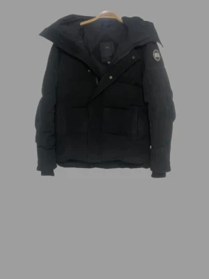 Canada goose mcmillian  - Säljer en svart pufferjacka från Canada Goose med stor huva och patch-logga på ärmen. Jackan har två stora framfickor och stängs med dragkedja och tryckknappar. Perfekt för kalla vinterdagar och riktigt snygg streetstil.                                               Osäker på om denna är en äkta Canada Goose — säljes som osäker autenticitet / eventuell repliken