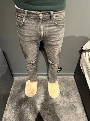 Nuddie jeans Grå slim fit  - Säljer ett par grå slim fit jeans med klassisk femficksdesign och normalhög midja. Jeansen har en snygg tvättad look och smala ben som sitter tight hela vägen ner. Passar perfekt till en avslappnad och trendig stil. Det är leans dean och säljs för grymt pris dessa är knappt använda och kostar 1600kr nypris. 29/30