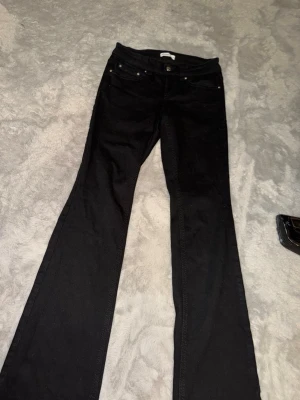 Svarta bootcut jeans - Snygga svarta jeans med bootcut-modell och klassisk femficksdesign. Jeansen har låg midja och är tillverkade i ett mjukt jeansmaterial som ger en bekväm passform. Perfekta för dig som gillar en tidlös och trendig look. Köpta för 500 kr 
