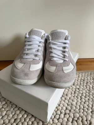 Maison Margiela Gats  - Snygga och stilrena Maison Margiela GATs i grå/vit färgkombination. Klassisk och tidlös modell som passar till både jeans, chinos och mer dressade outfits. Storlek 44,5. Väldigt mycket kvar att ge. Väldigt bra skick. 
