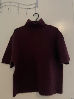 Vinröd stickad tröja Gina Tricot - Mysig vinröd stickad tröja från Gina Tricot i ullblandning. Tröjan har hög krage och halvlånga ärmar, perfekt för lager på lager. Enkel och stilren design som passar till mycket.