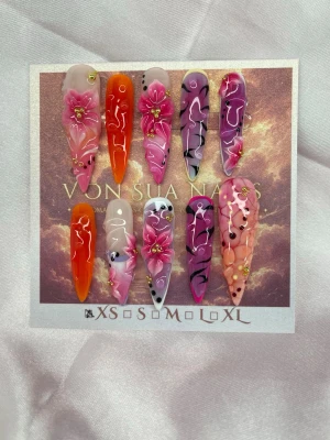 Zahara (XS);ExtraLongStiletto  - Handgjord extra långa stiletto press-on naglar i mixade färger som rosa, orange och lila. Naglarna har spetsig form och dekoreras med 3D-blommor, pärlor och handmålade detaljer. Perfekt för dig som vill ha unika och kreativa naglar med wow-effekt.XS: 14 mm, 11 mm, 11,5 mm, 10 mm, 8 mm