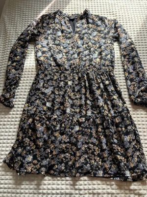 Blommig svart kortklänning - Söt svart kortklänning med blommigt mönster i beige, vitt och ljusblått. Tillverkad i ett tunt, luftigt material som känns skönt mot huden. Så snygg men kommer tyvärr inte till användning. Är i storlek 14y / 164 men passar mig som vanligtvis bär Xs / s 💞