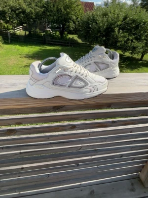 Vita chunky sneakers med meshdetaljer - Säljer ett par vita chunky sneakers med grå och silverfärgade meshdetaljer och tjock sula. Skorna har snörning och en modern, sportig look. Perfekta för dig som gillar streetwear och vill ha bekväma skor med stil.