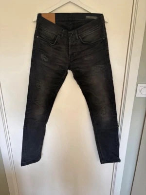 Dondup jeans - Säljer ett par grå skinny jeans med slitningar och distressed detaljer på framsidan. Jeansen har fem fickor, låg midja och smal passform. Perfekta för en avslappnad och trendig look. Slitningarna går ej igenom, skirv vid eventuella frågor, pris ej hugget i sten, 