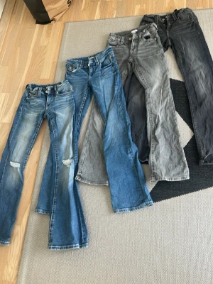 Fyra par jeans i olika tvättar - Fyra par jeans i olika blå och grå tvättar, vissa med slitningar och hål på knäna. Modellerna lätt utsvängda ben. Alla i stl 158 och samt är från Gina tricot.