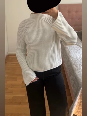 Vit ribbstickad tröja - Säljer en vit ribbstickad tröja med hög krage och vida ärmar. Tröjan har en relaxed fit och är gjord i ett tjockare material.Perfekt att styla med jeans eller vida byxor för en clean look.