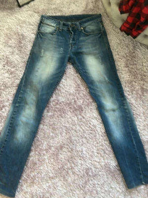 Blå D&G jeans med slitningar - Säljer ett par blå jeans från D&G med snygga slitningar och tvättade detaljer. Klassisk femficksmodell med dragkedja och knapp, samt D&G-logga på bakfickan. Jeansen har smal passform och är tillverkade i denim.