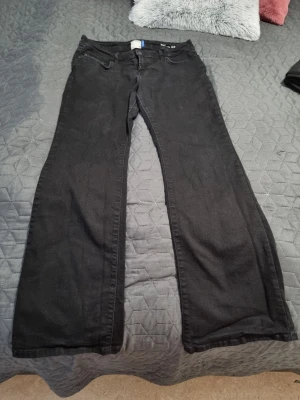 Svarta utsvängda jeans från L.T.B - Säljer ett par svarta jeans med utsvängda ben och klassisk femficksmodell. Jeansen har medel midja och är tillverkade i denimtyg som ger en skön passform. Perfekta för dig som gillar en retro och avslappnad stil. Använd fåtal gånger I storlek 30/32 motsvarar 40-42. Den är fint svart men på bilden ser ljusare ut på grund av kameran.