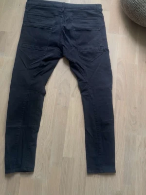 Svarta D-Staq slim jeans  - Säljer ett par svarta jeans med slim passform i storlek W33 och L32 med klassiska bakfickor. Jeansen har en enkel design med knapp och dragkedja framtill samt raka ben. Perfekta till en avslappnad stil.