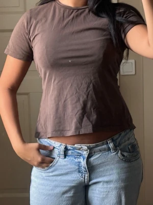 Brun basic t-shirt i bomull - En enkel brun t-shirt i mjuk bomull med korta ärmar och rund hals. Passformen är normal och modellen är klassisk utan tryck eller mönster. Perfekt att matcha med jeans eller shorts för en avslappnad look.