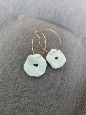 Handgjorda steninspirerade örhängen - Unika örhängen med tunna guldfärgade ringar och oregelbundna, steninspirerade hängen. Ringarna har en diameter på 2,5 cm. Örhängena är gjorda för hand av mig i polymerlera. 
