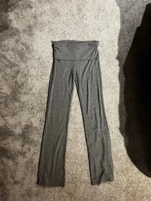 Grå yogapants från Gina Tricot Young  - Säljer grå yogapants från Gina Tricot Young med låg midja. Har remmat material. Perfekta för en avslappnad och chill stil.