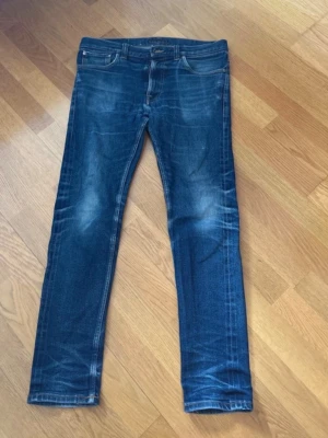 Nudie jeans - Nudie jeans lean dean i storlek W33 L32, fräsch mörkblå wash. Knappen var trasig därför det är en ny knapp. Hör av er ang pris!