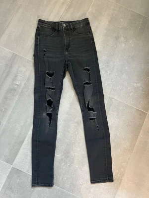 Svarta skinny jeans med slitningar - Säljer ett par svarta skinny jeans med hög midja och slitningar, de har en liten fläck på ena knät se sista bild💕