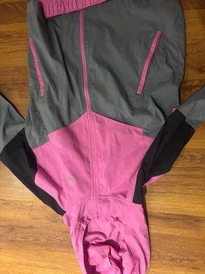 Nike träningsset rosa och grå - Säljer ett sportigt träningsset från Nike med huvtröja i rosa, grått och svart samt matchande rosa byxor. Setet har dragkedja, huva och vita Nike-loggor. 