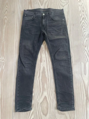 Nudie jeans - Säljer mina mörkgråa Nudie Jeans i strlk 32/32 och modellen Lean Dean. Byxorna är i riktigt bra skick och inga defekter/hål finns. Klassisk femficksdesign och går att klä med allt!
